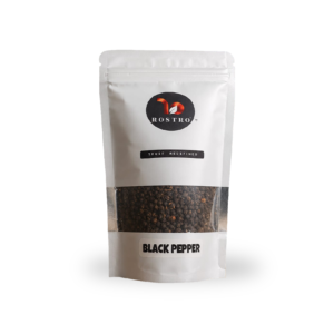 ROSTRO brand whole black pepper package displayed in a natural forest landscape during sunset.